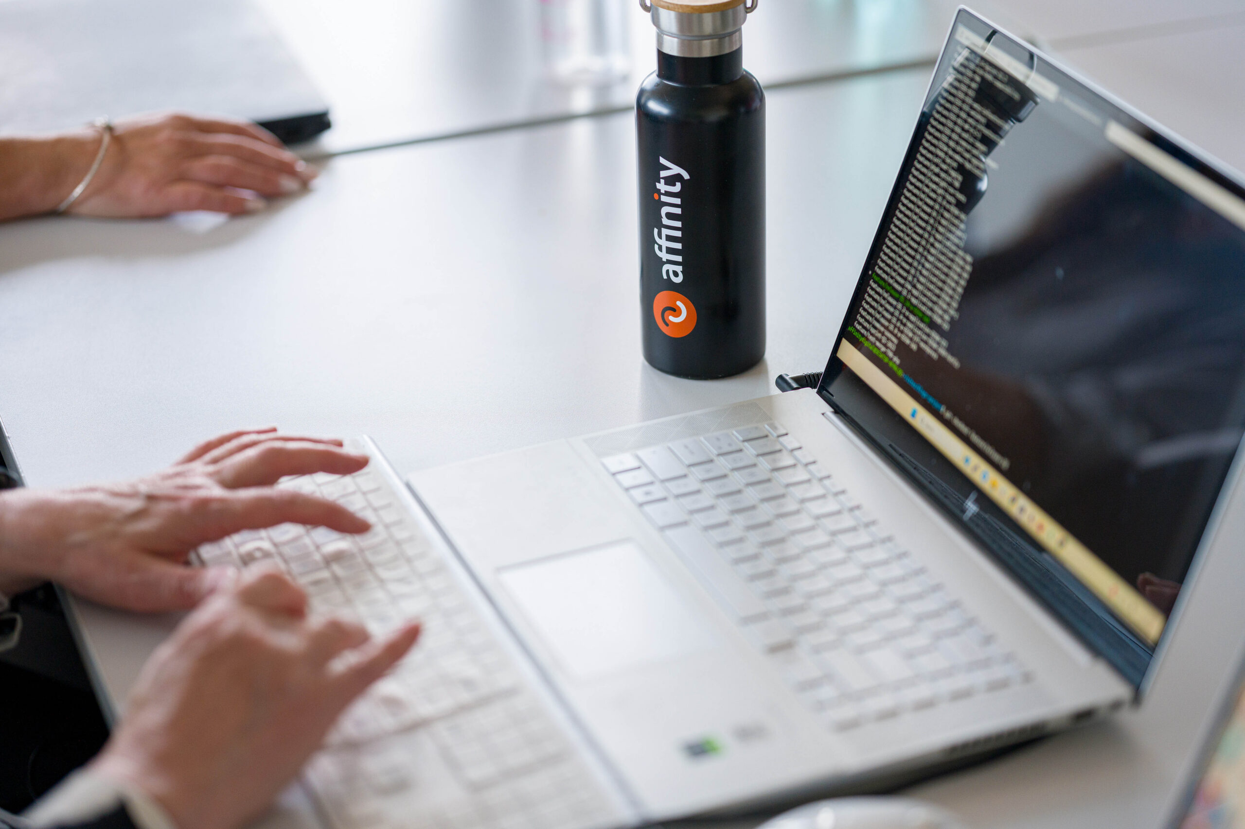 Hands on laptop working with Affinity water bottle 